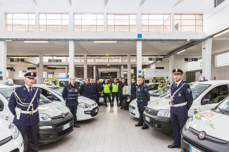Agenti di polizia municipale in un garage con auto.
