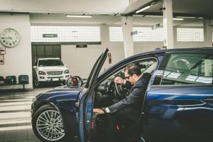 Uomo in auto blu dentro un garage.