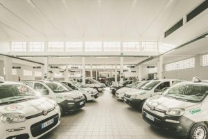 Parcheggio coperto con diverse auto bianche allineate.