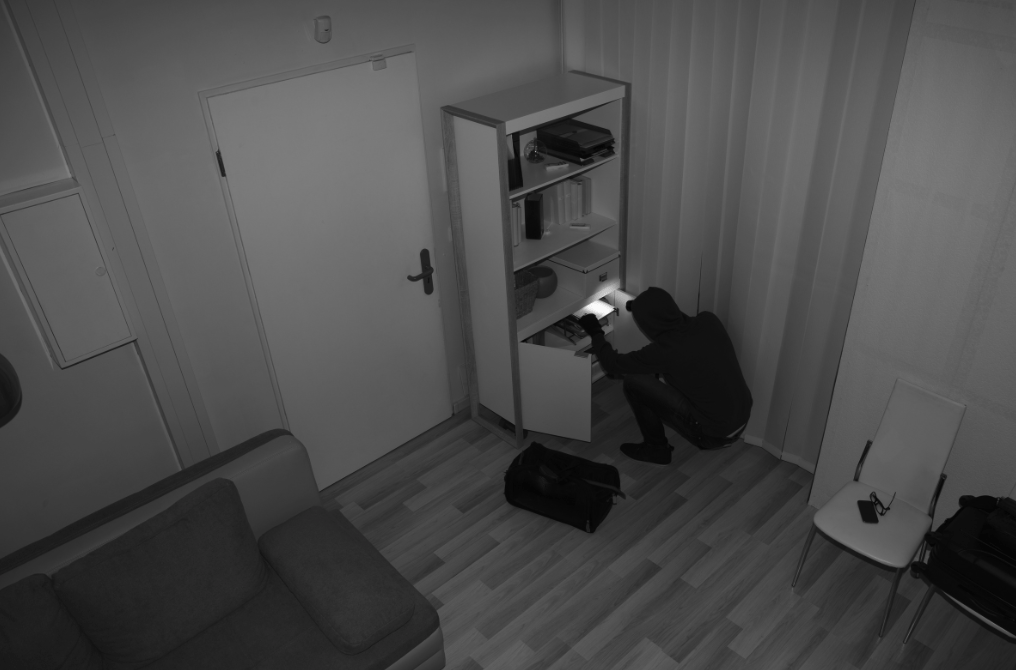 Persona in nero fruga in un armadio aperto.